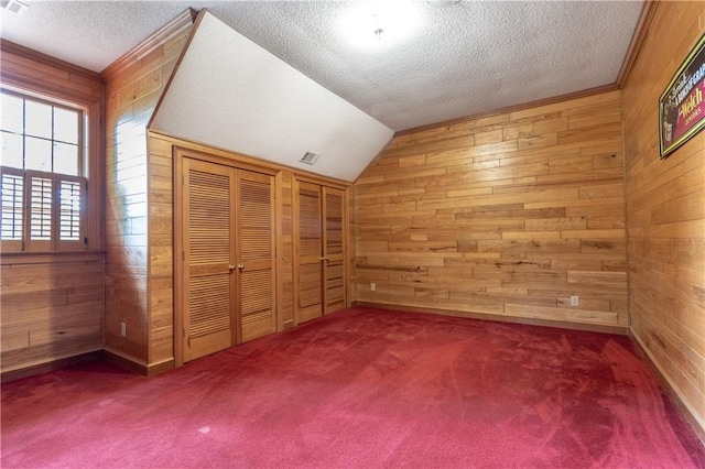 bonus room featuring vaulted ceiling, wood walls, carpet floors, and a textured ceiling