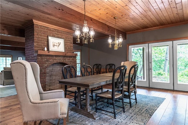 dining room with hardwood / wood-style floors, wood ceiling, ornamental molding, and an inviting chandelier