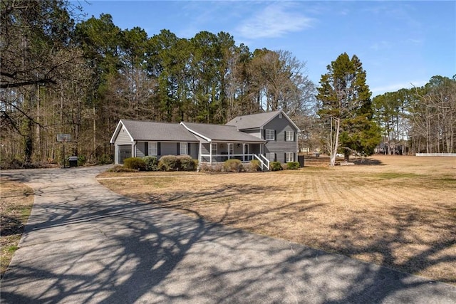 tri-level home with covered porch, driveway, a front lawn, and a garage