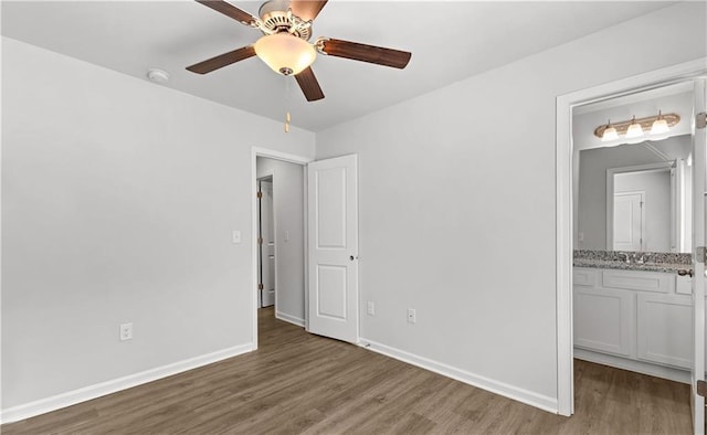 unfurnished bedroom featuring ceiling fan, dark hardwood / wood-style floors, and connected bathroom