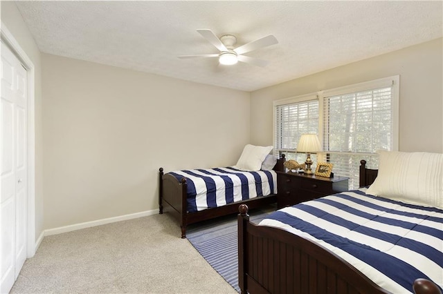 carpeted bedroom with ceiling fan, a closet, baseboards, and a textured ceiling