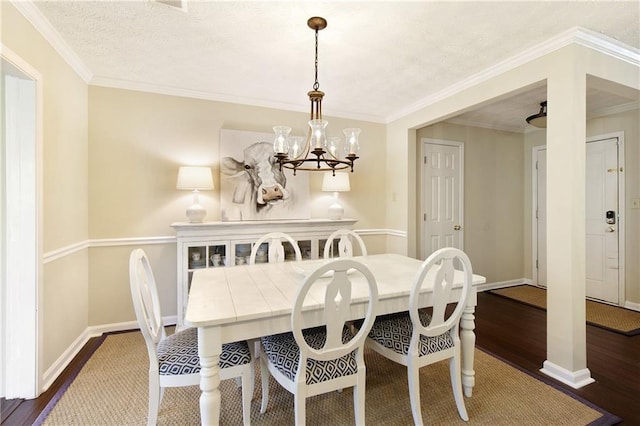 dining room with a chandelier, crown molding, baseboards, and wood finished floors