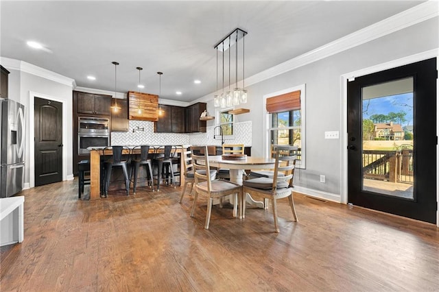 dining area featuring dark wood finished floors, baseboards, and ornamental molding