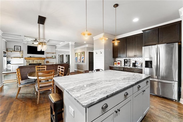 kitchen featuring a ceiling fan, decorative columns, a fireplace, stainless steel fridge, and open floor plan