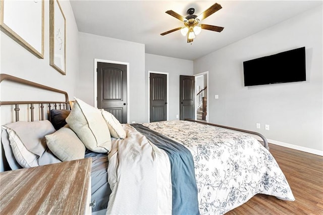 bedroom with a ceiling fan, wood finished floors, and baseboards