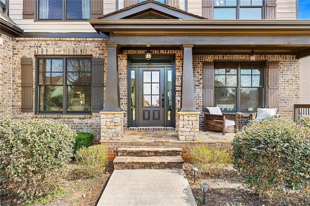 view of exterior entry featuring brick siding and covered porch