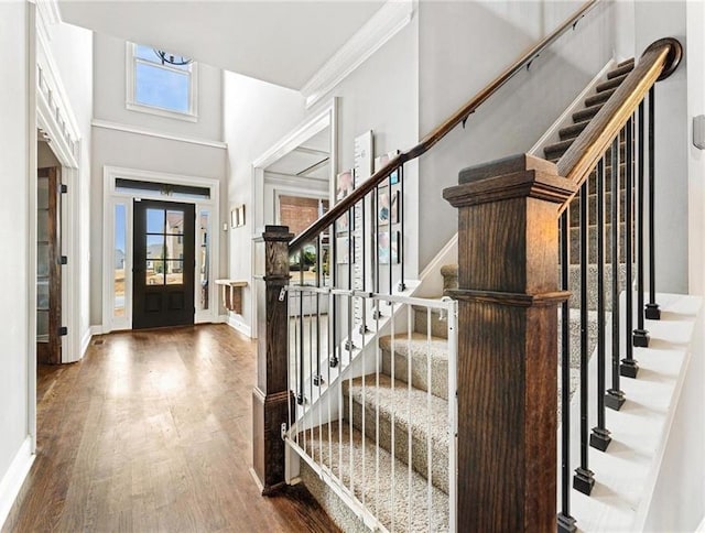 entryway featuring baseboards, wood finished floors, stairs, and ornamental molding