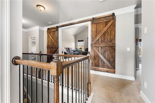 stairway with visible vents, baseboards, a barn door, ornamental molding, and carpet flooring