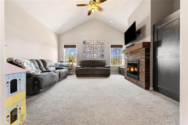 carpeted living area with ceiling fan, visible vents, high vaulted ceiling, and a glass covered fireplace