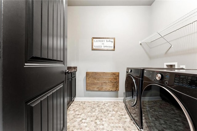 clothes washing area featuring baseboards, separate washer and dryer, and laundry area