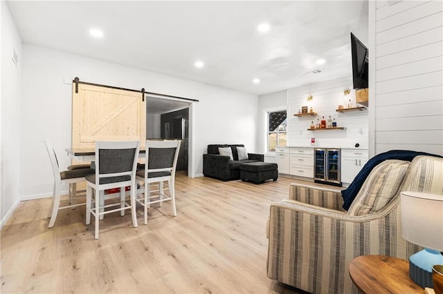 dining area with light wood finished floors, recessed lighting, wine cooler, a barn door, and a dry bar