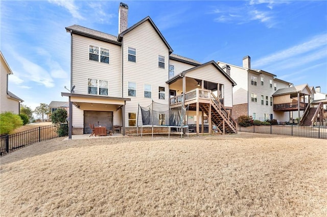 rear view of property with a chimney, stairs, a trampoline, and fence