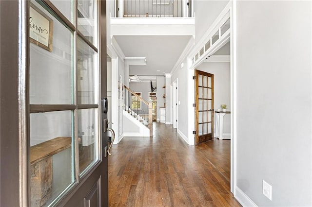 foyer entrance featuring stairway, wood finished floors, baseboards, and ornamental molding