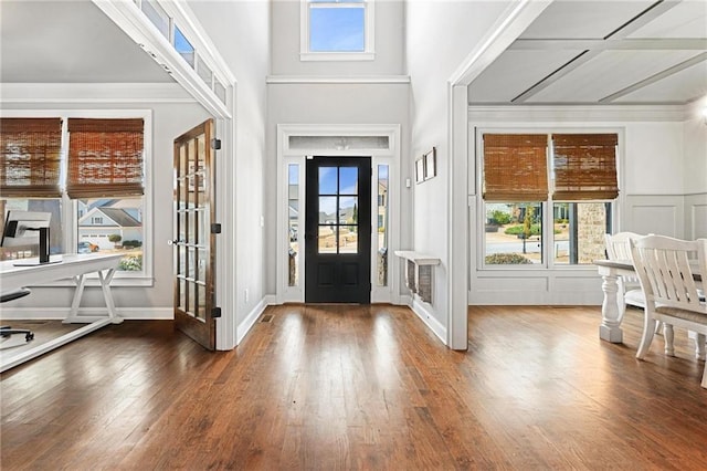 entryway with hardwood / wood-style floors, crown molding, a decorative wall, and plenty of natural light