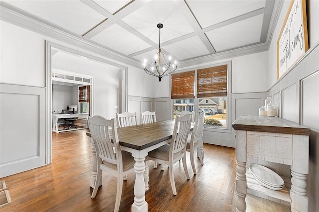 dining space with an inviting chandelier, a decorative wall, wood finished floors, and coffered ceiling