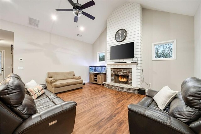 living room featuring a fireplace, visible vents, vaulted ceiling, wood finished floors, and baseboards