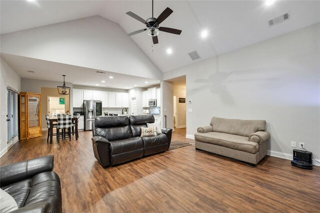 living area featuring high vaulted ceiling, a fireplace, wood finished floors, visible vents, and a ceiling fan