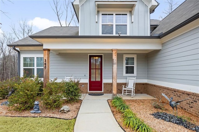 property entrance featuring a porch, board and batten siding, and brick siding