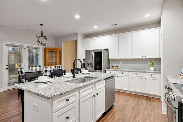 kitchen with appliances with stainless steel finishes, a sink, light wood-style flooring, and white cabinetry