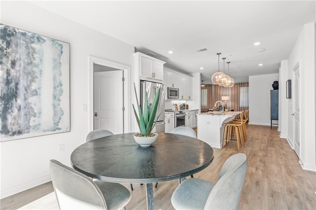 dining area featuring light wood-type flooring and sink