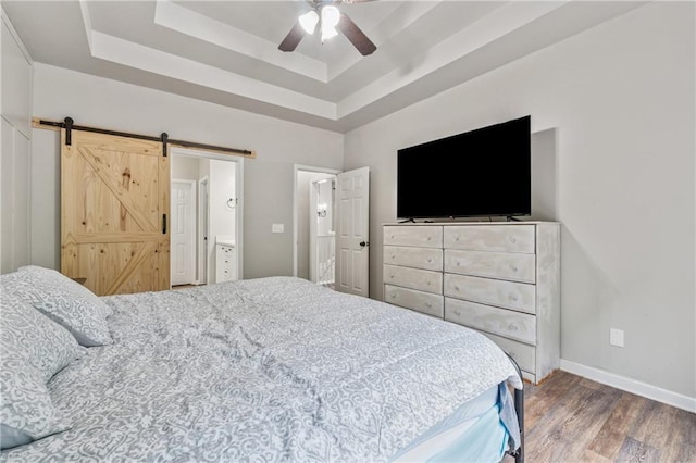 58 Hampton Forest Ct, Dahlonega, GA 30533 - bedroom with a tray ceiling, wood finished floors, a barn door, baseboards, and a ceiling fan