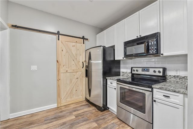 58 Hampton Forest Ct, Dahlonega, GA 30533 - kitchen featuring appliances with stainless steel finishes, a barn door, light wood-type flooring, white cabinets, and decorative backsplash