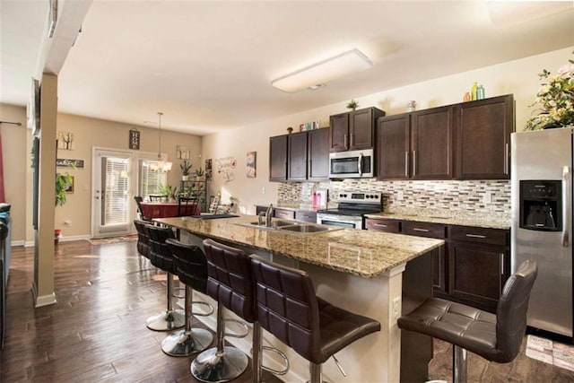 kitchen with sink, hanging light fixtures, a breakfast bar area, a kitchen island with sink, and appliances with stainless steel finishes