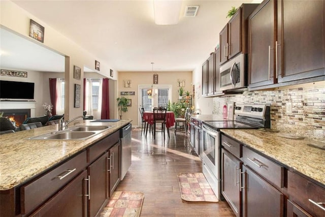 kitchen featuring light stone countertops, sink, backsplash, decorative light fixtures, and appliances with stainless steel finishes