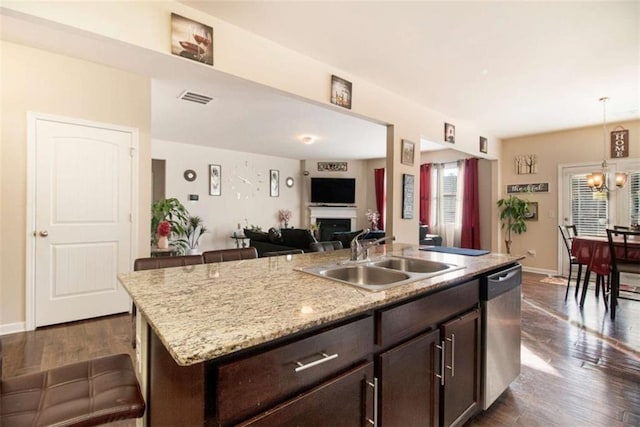 kitchen featuring pendant lighting, dishwasher, a center island with sink, sink, and dark brown cabinets