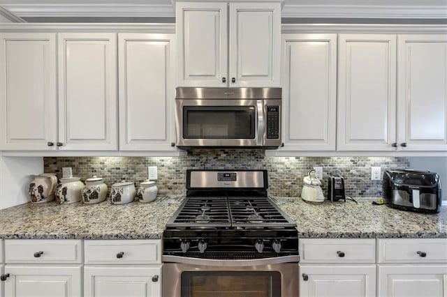 kitchen featuring decorative backsplash, appliances with stainless steel finishes, white cabinetry, and light stone counters