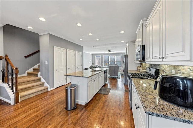 kitchen with light hardwood / wood-style flooring, white cabinetry, an island with sink, and stainless steel appliances