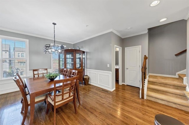 dining area with a notable chandelier, wood-type flooring, and ornamental molding