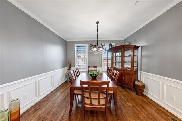 dining room featuring dark hardwood / wood-style floors, ornamental molding, and a chandelier