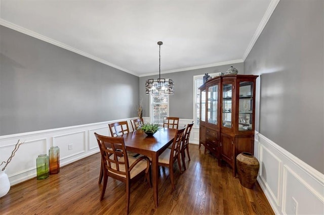 dining space featuring dark hardwood / wood-style flooring, ornamental molding, and an inviting chandelier