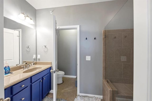 bathroom with tile patterned floors, vanity, tiled shower, and toilet