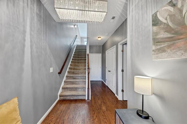 stairs with hardwood / wood-style floors and an inviting chandelier