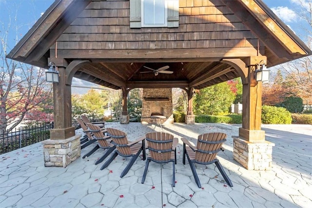 view of patio with a gazebo and an outdoor stone fireplace