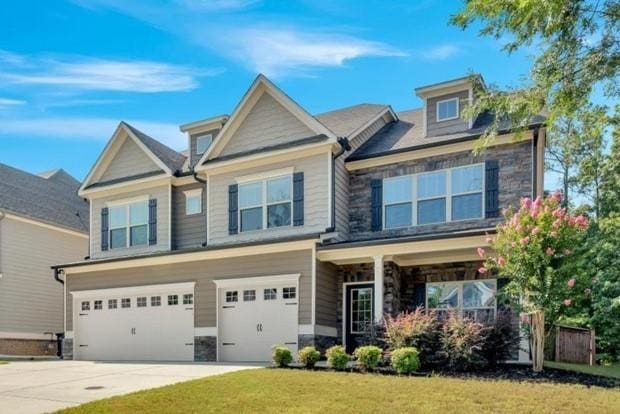 craftsman house with stone siding, a front lawn, concrete driveway, and a garage