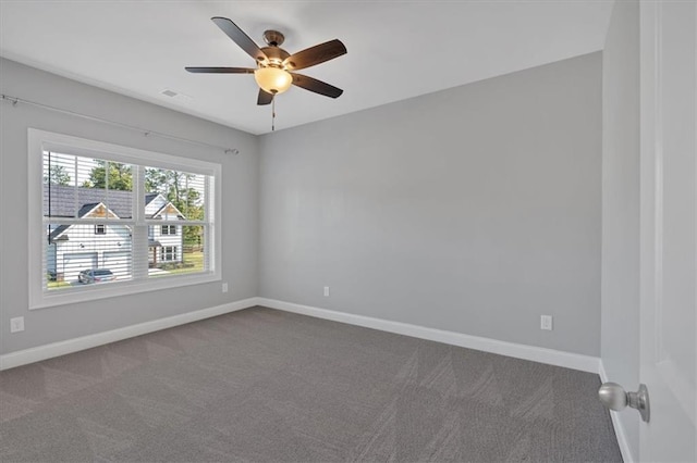 empty room with visible vents, baseboards, dark carpet, and a ceiling fan