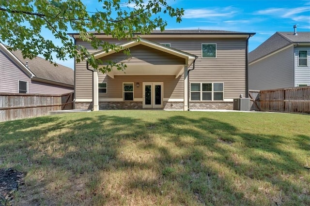 back of property with a fenced backyard, central AC unit, and a lawn
