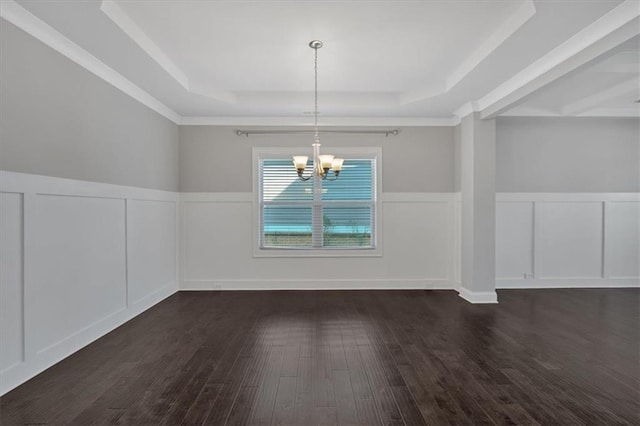 unfurnished dining area featuring wood finished floors, a tray ceiling, wainscoting, a decorative wall, and a chandelier