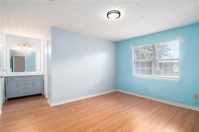 256 Olde Oaks Ln, Riverdale, GA 30274 - unfurnished bedroom with light wood finished floors, a textured ceiling, baseboards, and ensuite bathroom