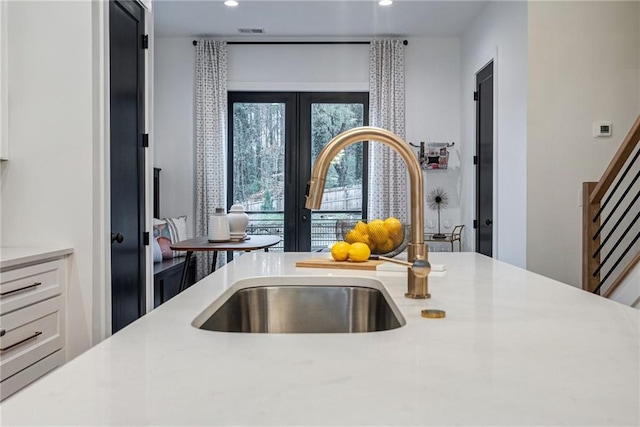 kitchen featuring a sink, light countertops, white cabinetry, recessed lighting, and french doors
