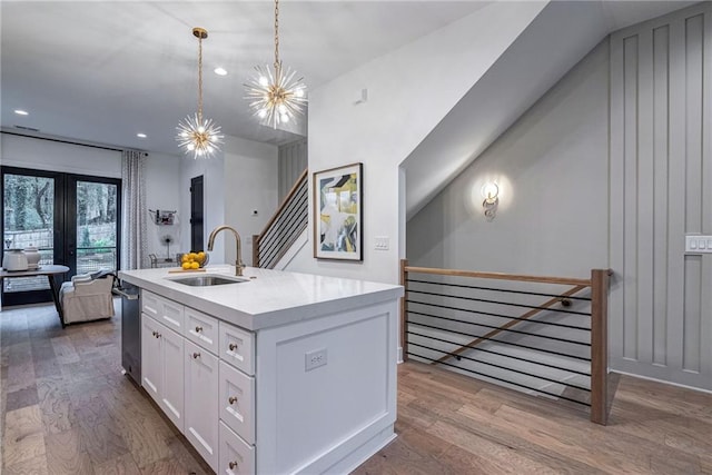kitchen with a sink, light countertops, wood finished floors, and white cabinets