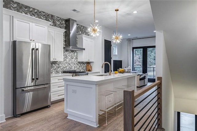 kitchen featuring visible vents, white cabinets, wall chimney range hood, light countertops, and freestanding refrigerator