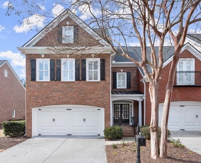 view of front of property with a garage, driveway, brick siding, and french doors