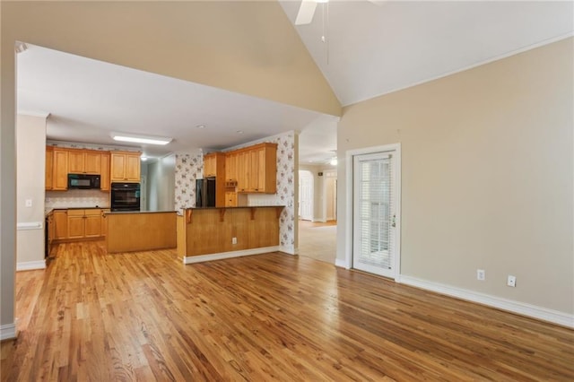 980 Ector Chase NW, Kennesaw, GA 30152 - kitchen with black appliances, a peninsula, light wood-style floors, ceiling fan, and high vaulted ceiling