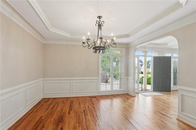 980 Ector Chase NW, Kennesaw, GA 30152 - unfurnished dining area with arched walkways, a raised ceiling, light wood-style floors, a decorative wall, and ornamental molding