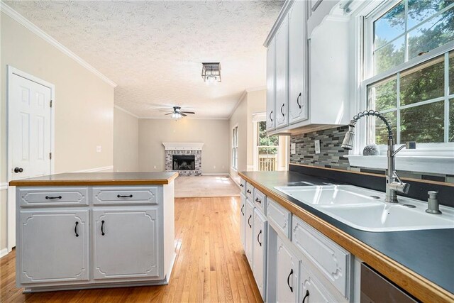 kitchen featuring a textured ceiling, light hardwood / wood-style flooring, backsplash, sink, and ceiling fan