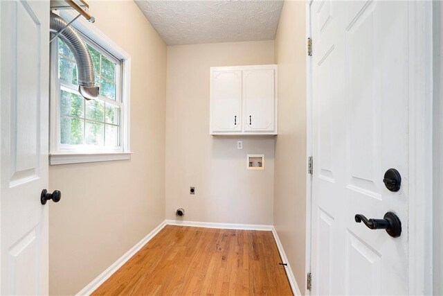 laundry room with hookup for a washing machine, light wood-type flooring, hookup for an electric dryer, cabinets, and a textured ceiling